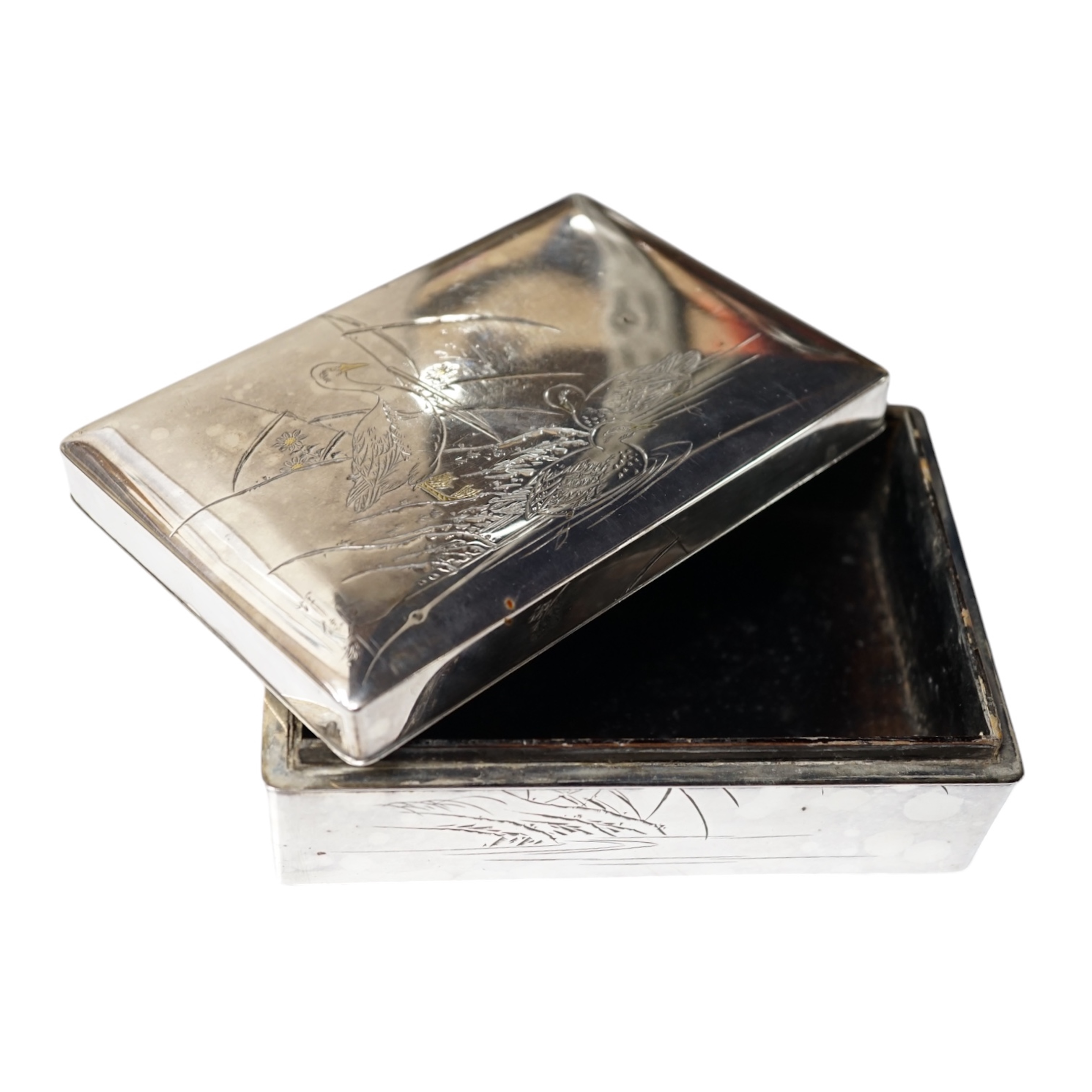 A Japanese white and yellow metal mounted rectangular cigarette box, engraved with birds and reeds, signed to the base, 14.2cm. Condition - fair